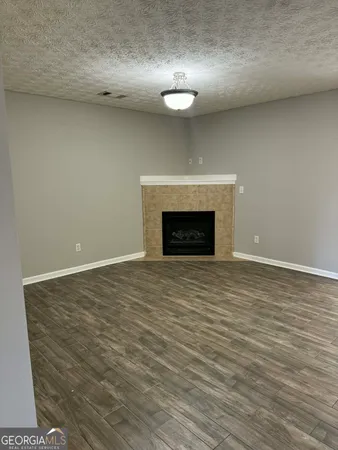 a view of an empty room with wooden floor and a fireplace