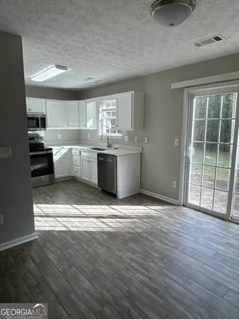 a large kitchen with kitchen island a stove a sink dishwasher and white cabinets with wooden floor