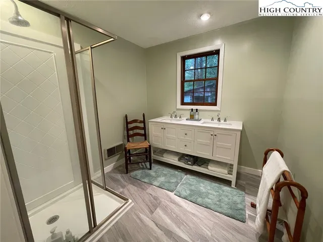a view of a hallway with wooden floor and a bathroom