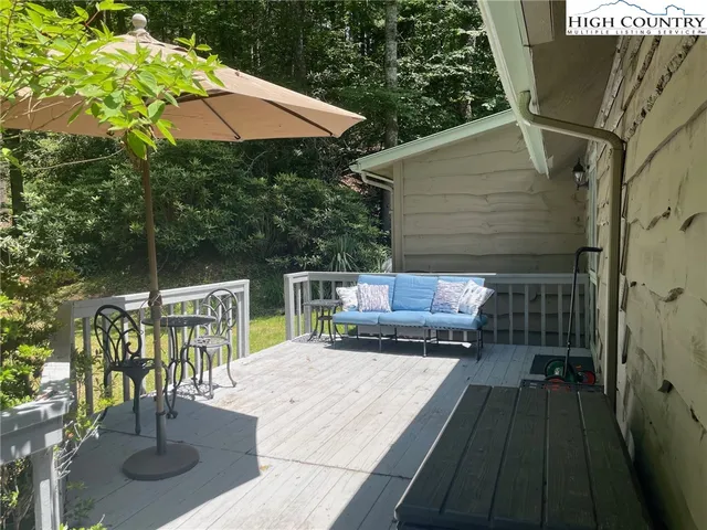 a view of a patio with couches table and chairs under an umbrella with a small yard
