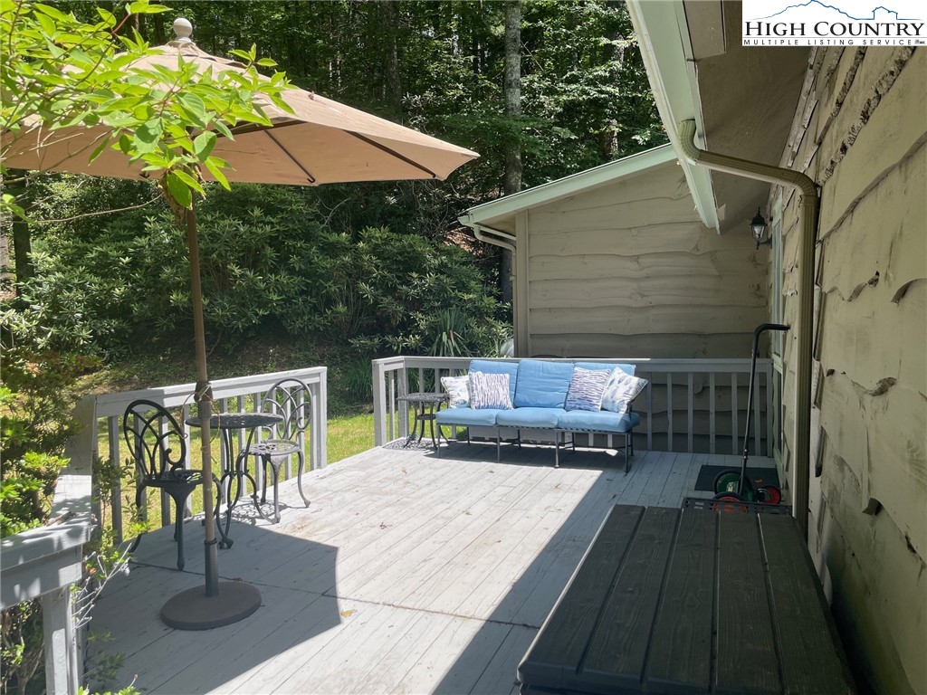 217 Holiday Hills Drive Boone, NC 28607 - Photo 8 of 47 a view of a patio with couches table and chairs under an umbrella with a small yard