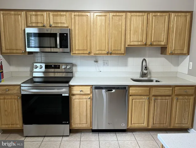 a kitchen with stainless steel appliances granite countertop white cabinets a sink and a granite counter