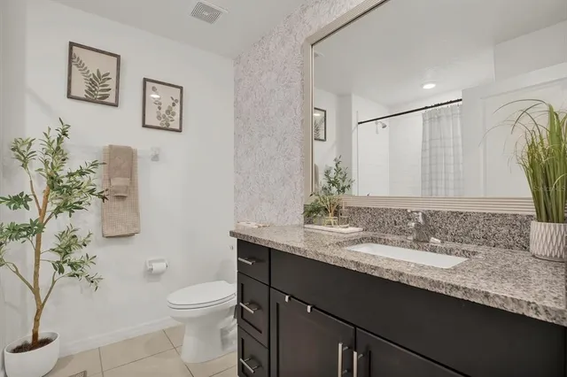 a bathroom with a granite countertop sink a toilet and a mirror
