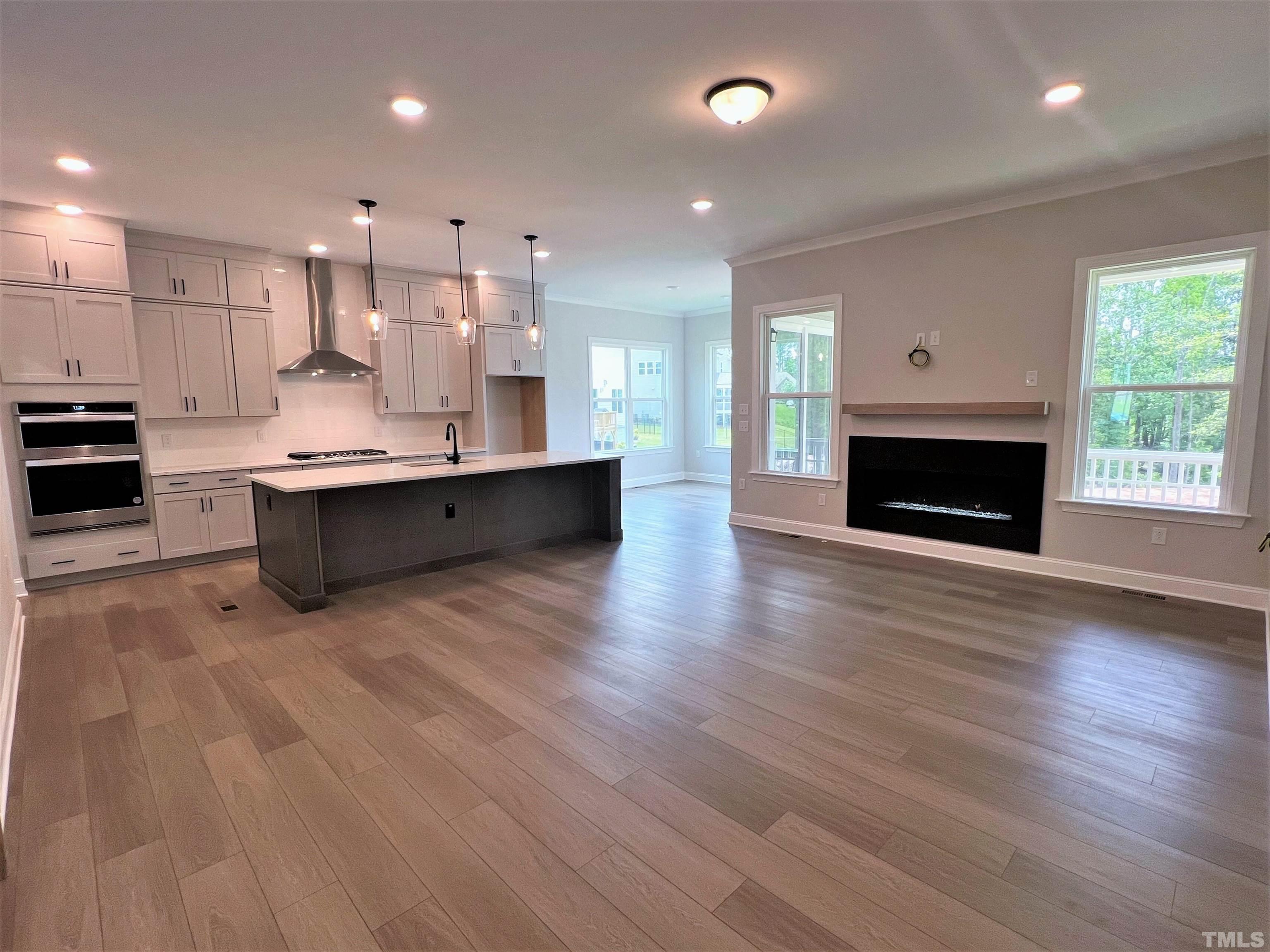 7629 Hasentree Way, Unit 519 Wake Forest, NC 27587 - Photo 26 of 76 a large white kitchen with kitchen island a stove a sink wooden floor and a fireplace