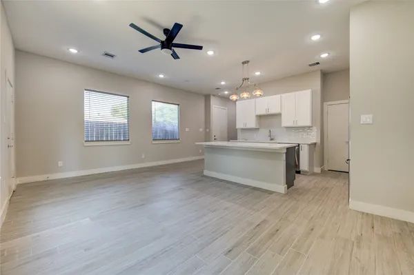 a view of an empty room with kitchen appliances and a ceiling fan