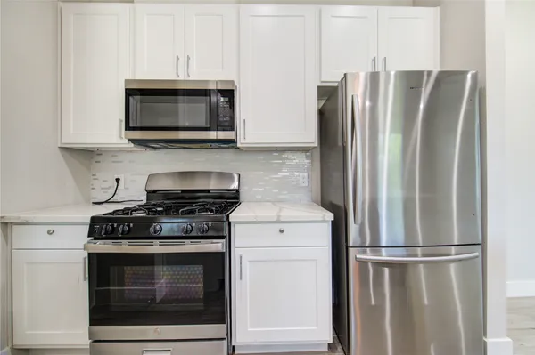 a kitchen with stainless steel appliances white cabinets white stove a microwave and a refrigerator