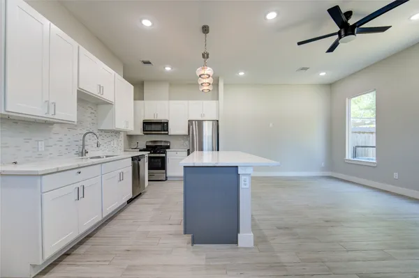 a large kitchen with stainless steel appliances kitchen island granite countertop a stove a sink and a refrigerator