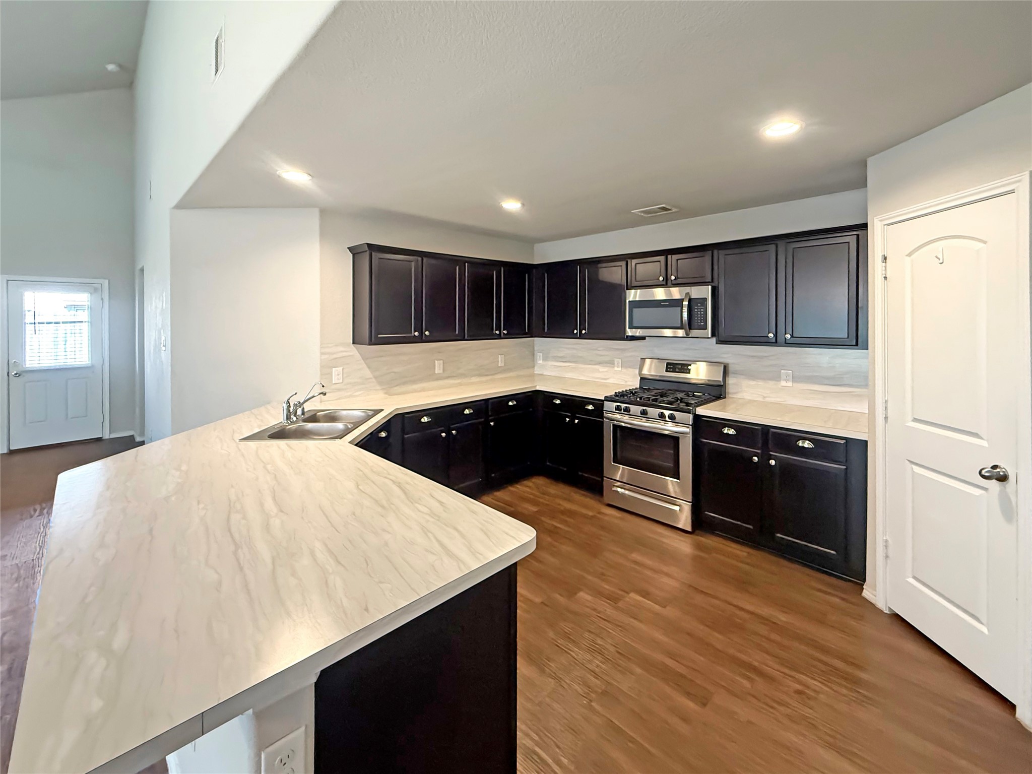 15443 Cipres Verde Street Channelview, TX 77530 - Photo 7 of 27 a large kitchen with stainless steel appliances kitchen island granite countertop a sink dishwasher a stove and a refrigerator with wooden floor