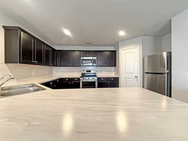 a large kitchen with a stove a refrigerator and a sink