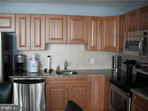 901 North Penn Street, Unit R903 Philadelphia, PA 19123 - Photo 6 of 18 a kitchen with stainless steel appliances granite countertop a stove a sink dishwasher and cabinets with wooden floor