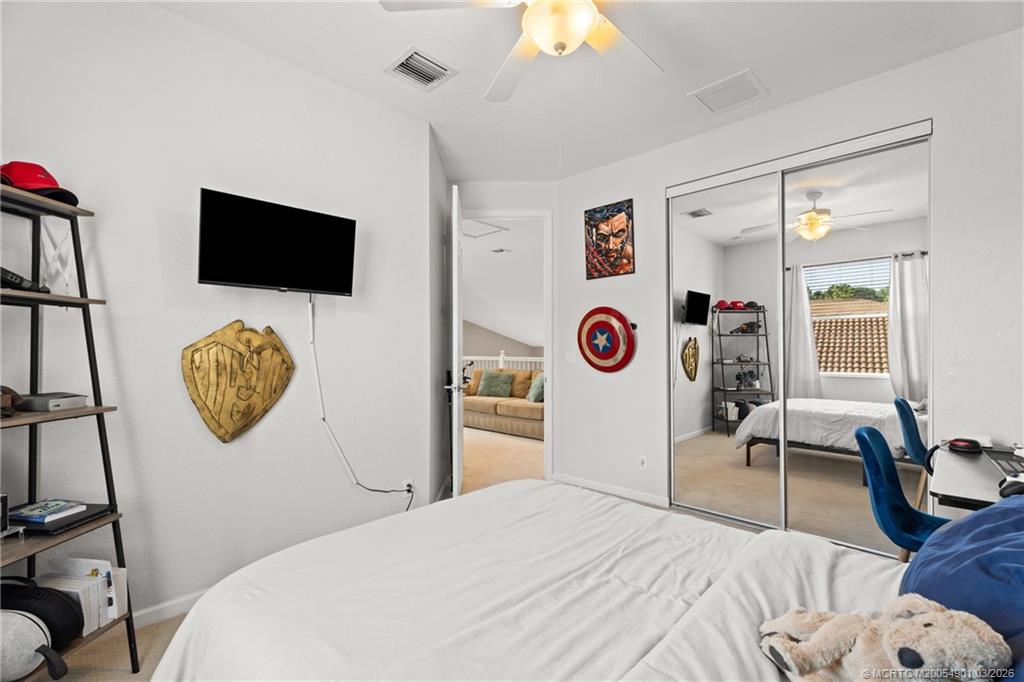 2973 Southwest Porpoise Circle Stuart, FL 34997 - Photo 20 of 47 a bedroom with a bed and a flat screen tv