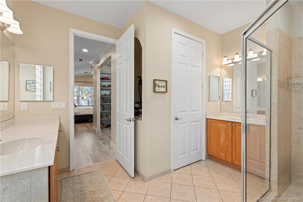 2973 Southwest Porpoise Circle Stuart, FL 34997 - Photo 25 of 47 a spacious bathroom with a glass shower door a bathtub a sink and a mirror