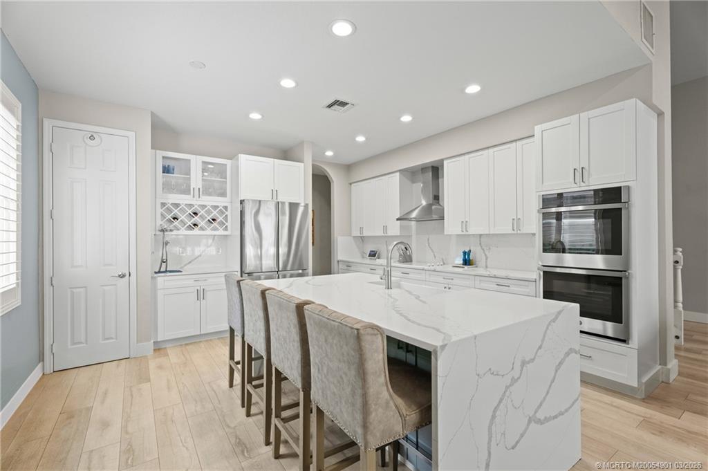 2973 Southwest Porpoise Circle Stuart, FL 34997 - Photo 9 of 47 a kitchen with refrigerator cabinets and wooden floor