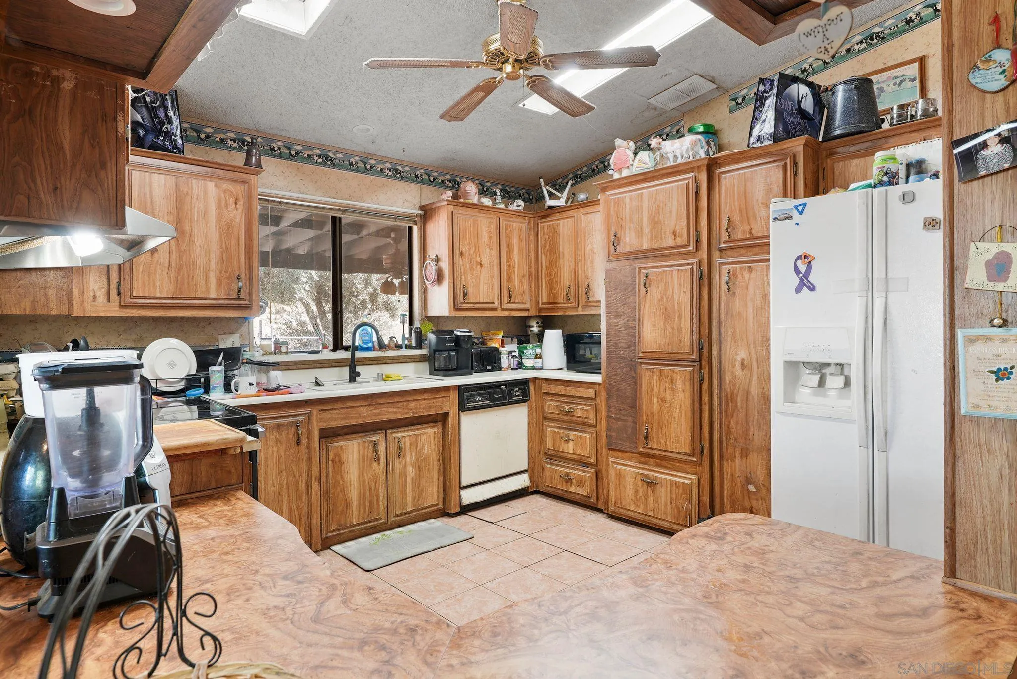 1070 Harris Ranch Road Potrero, CA 91963 - Photo 13 of 58 a kitchen with granite countertop a refrigerator a sink dishwasher a stove top oven a dining table and chairs with wooden floor