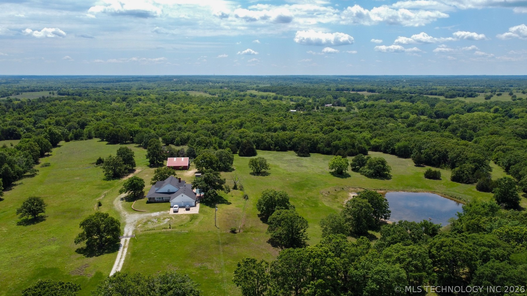 13248 North 3540th Road Maud, OK 74854 - Photo 30 of 98 Expansive rural property featuring a main residence, a secondary red-roofed structure, a private pond, and mature trees