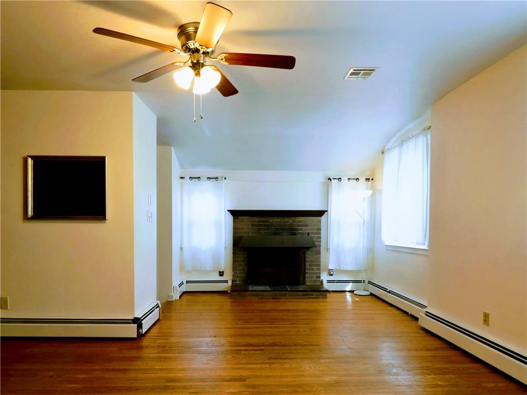 172 Harrison Street Emmaus, PA 18049 - Photo 2 of 30 A classic brick fireplace anchors this inviting living space, complemented by warm hardwood flooring.