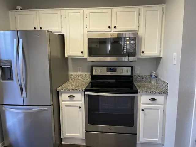 a kitchen with stainless steel appliances white cabinets and a refrigerator