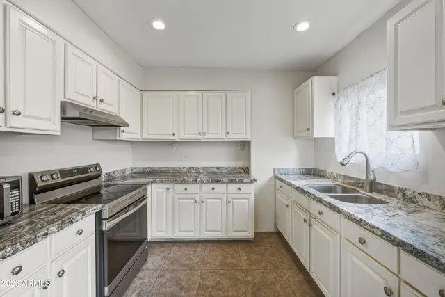 a kitchen with stainless steel appliances granite countertop a sink stove and cabinets