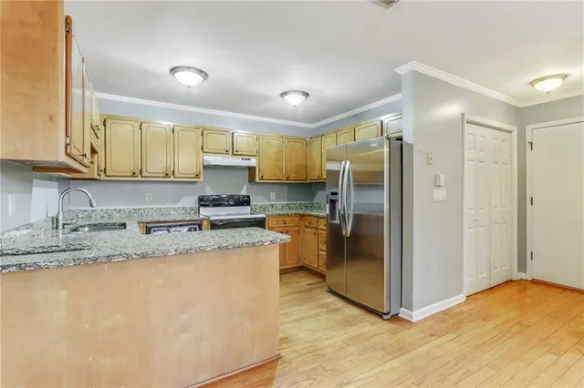 a kitchen with stainless steel appliances granite countertop a refrigerator a sink a stove and oven