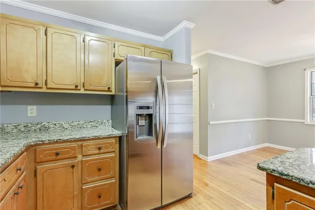a kitchen with granite countertop a refrigerator and cabinets