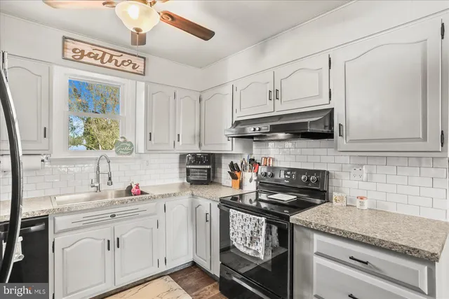 a kitchen with granite countertop white cabinets and a stove