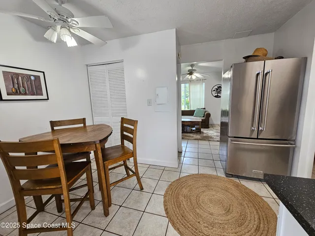 a kitchen with stainless steel appliances granite countertop a dining table chairs and a refrigerator