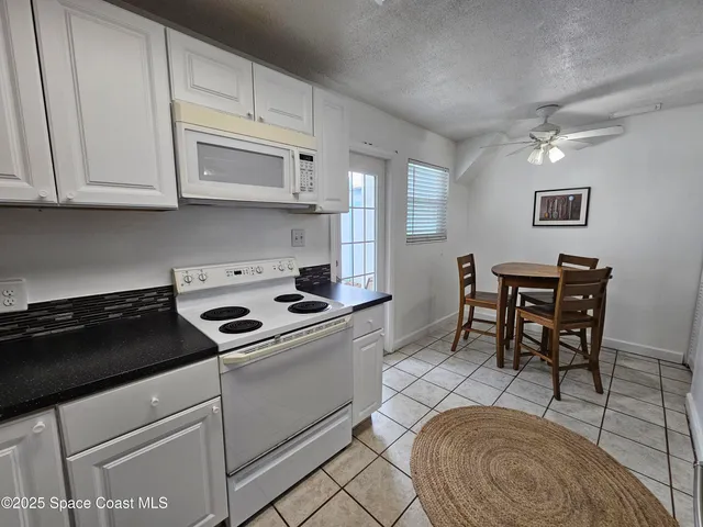 a kitchen with stainless steel appliances granite countertop a stove a sink dishwasher and white cabinets with wooden floor