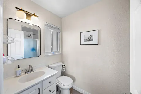 a bathroom with a toilet sink vanity and mirror