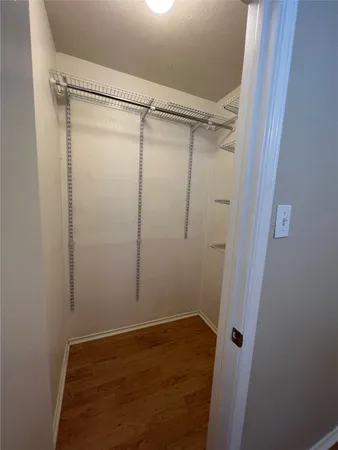 an empty room with wooden floor chandelier fan and windows