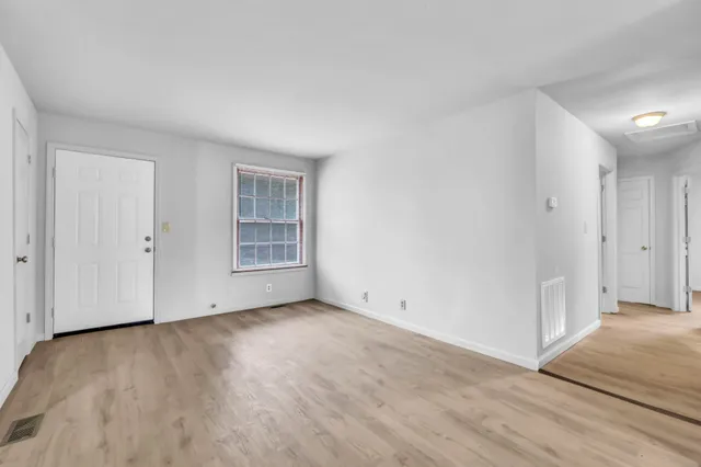 a view of an empty room with wooden floor and a window