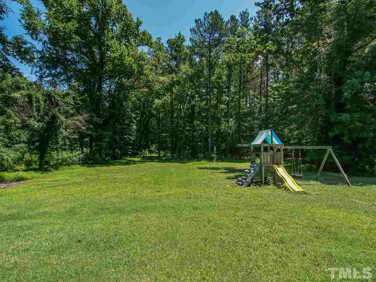 10001 Fanny Brown Road Raleigh, NC 27603 - Photo 24 of 25 a view of a backyard with a slide trees and wooden fence