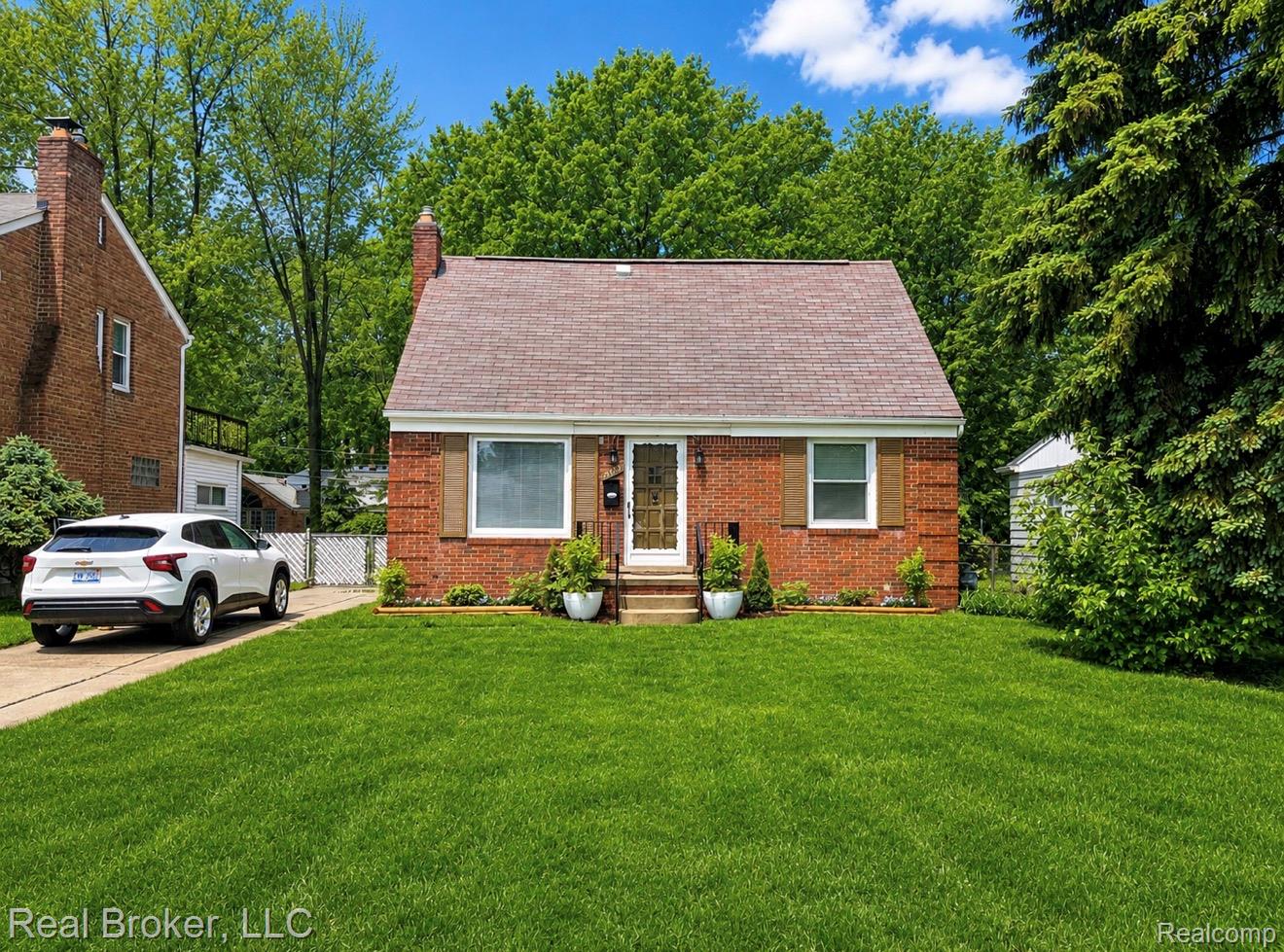 View of front of property with brick siding, a front yard, a chimney, and a shingled roof