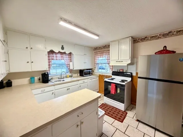 a kitchen with granite countertop a refrigerator stove top oven and sink