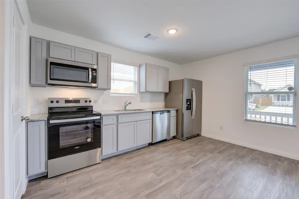 a kitchen with granite countertop a refrigerator and a stove top oven
