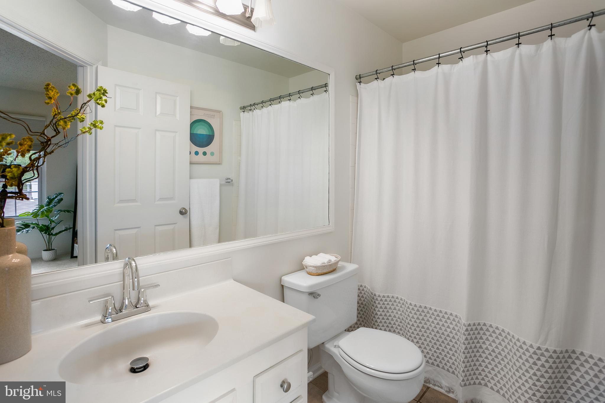 6542 Cypress Point Road Alexandria, VA 22312 - Photo 18 of 31 a bathroom with a sink a toilet and shower curtain