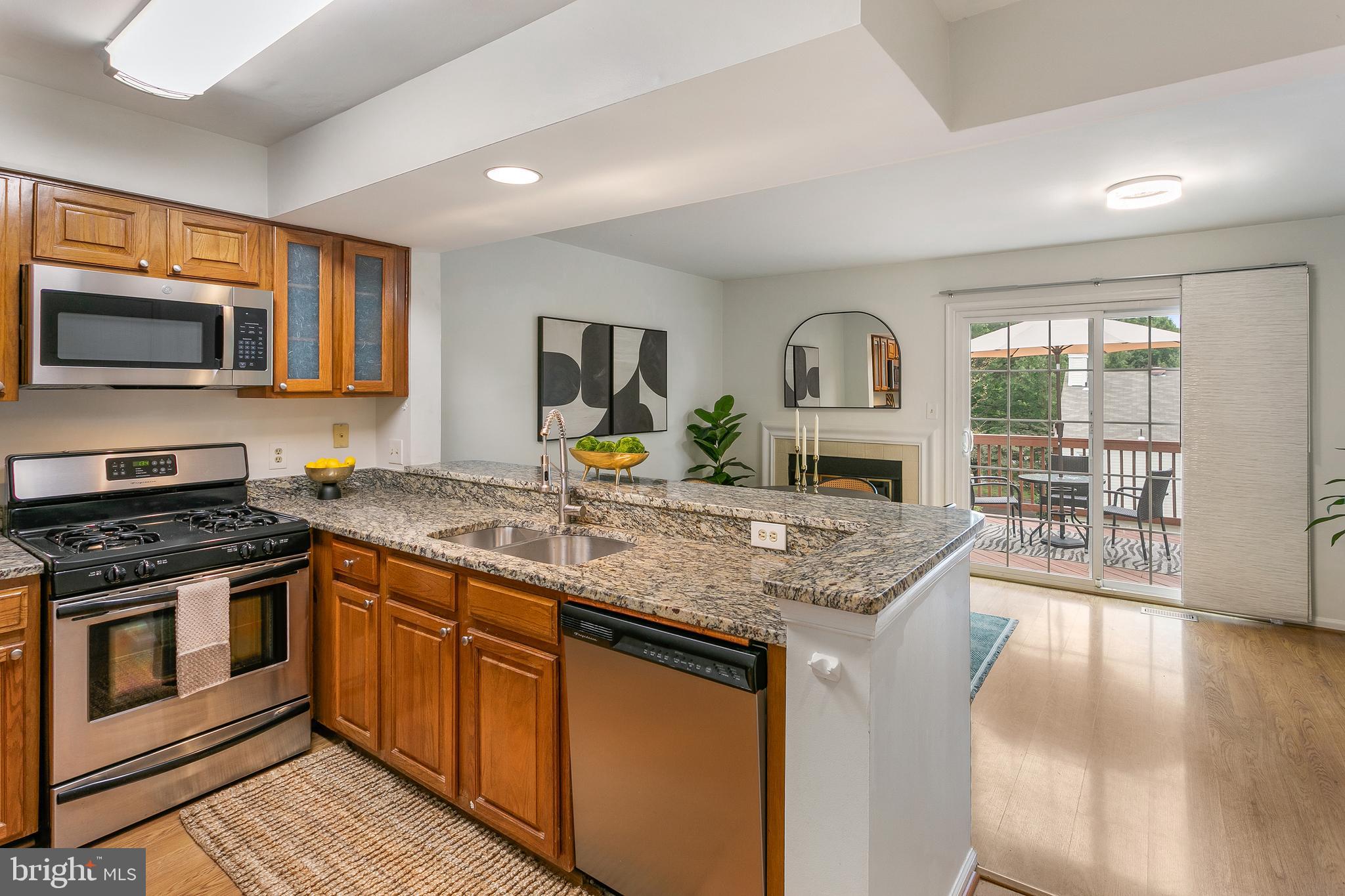 6542 Cypress Point Road Alexandria, VA 22312 - Photo 8 of 31 a kitchen with stainless steel appliances granite countertop a stove top oven a sink dishwasher a dining table and chairs with wooden floor