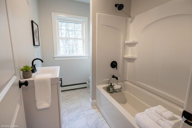 a bathroom with a tub a sink a window and a shower