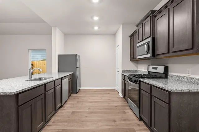 a kitchen with stainless steel appliances granite countertop a stove a sink and a refrigerator