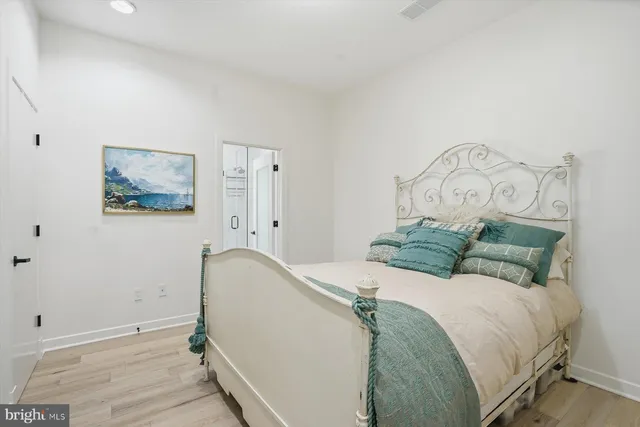 a bed sitting in a bedroom next to a window and a wooden floor