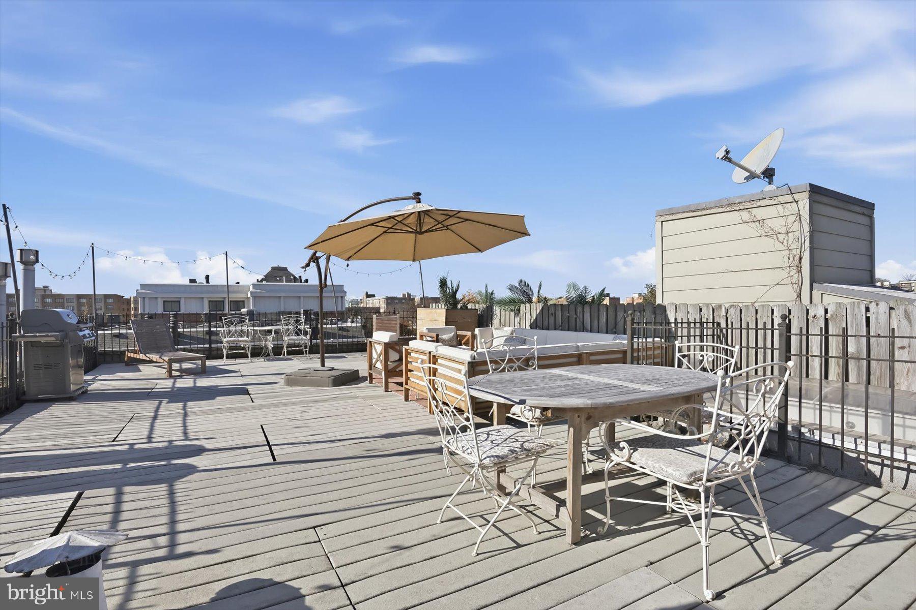 1741 Johnson Avenue Northwest, Unit 302 Washington, DC 20009 - Photo 22 of 24 a view of a roof deck with table and chairs under an umbrella