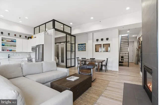 a living room with furniture and a dining table with wooden floor