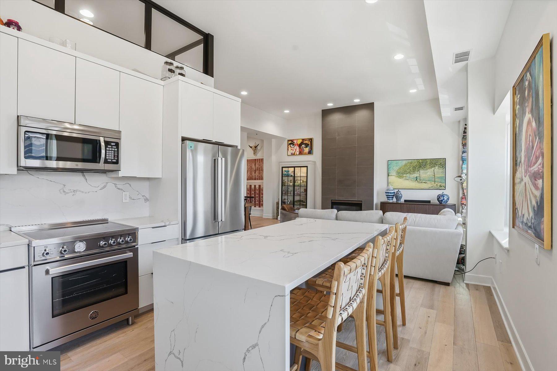 1741 Johnson Avenue Northwest, Unit 302 Washington, DC 20009 - Photo 8 of 24 a kitchen with stainless steel appliances a stove a refrigerator island a oven with white cabinets and wooden floor
