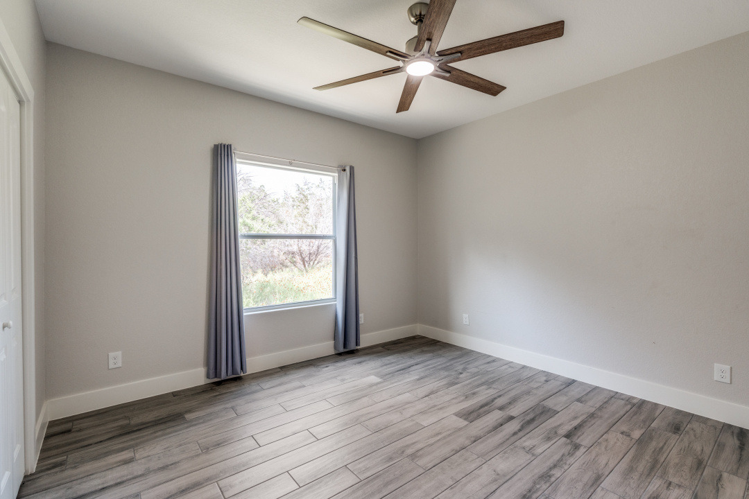 1848 Tanglewood Trail Spring Branch, TX 78070 - Photo 9 of 12 A well-lit bedroom features wood flooring and a modern ceiling fan for ultimate comfort.