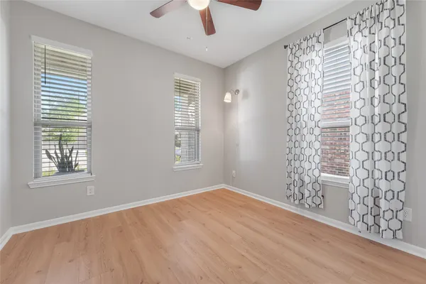 a view of an empty room with a window and wooden floor