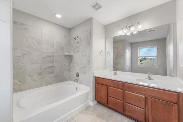 a bathroom with a tub a double vanity sink and a mirror