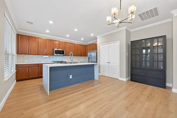 a kitchen with stainless steel appliances granite countertop a sink dishwasher a stove and a refrigerator with wooden floor