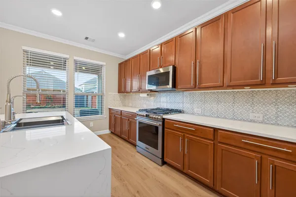 a kitchen with stainless steel appliances granite countertop a stove a sink and a microwave