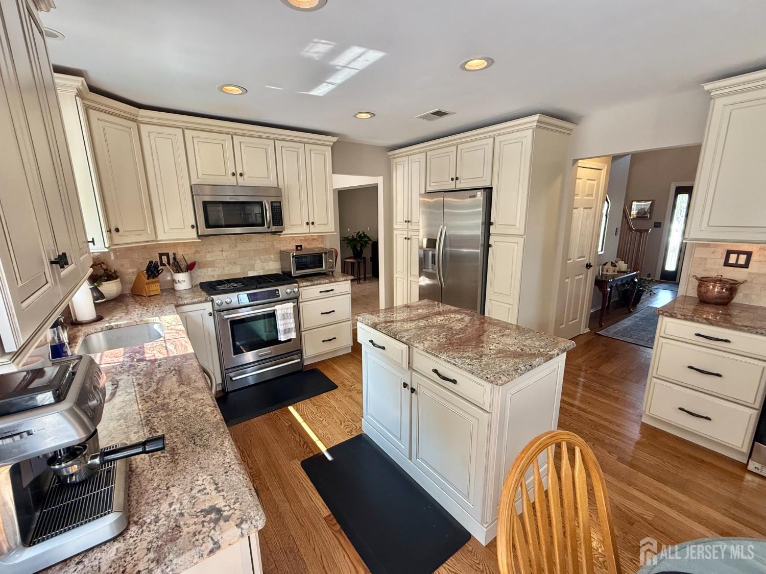 44 Diamond Lane Howell, NJ 07731 - Photo 6 of 35 a kitchen with stainless steel appliances granite countertop a stove top oven a sink dishwasher a refrigerator and a dining table with wooden floor