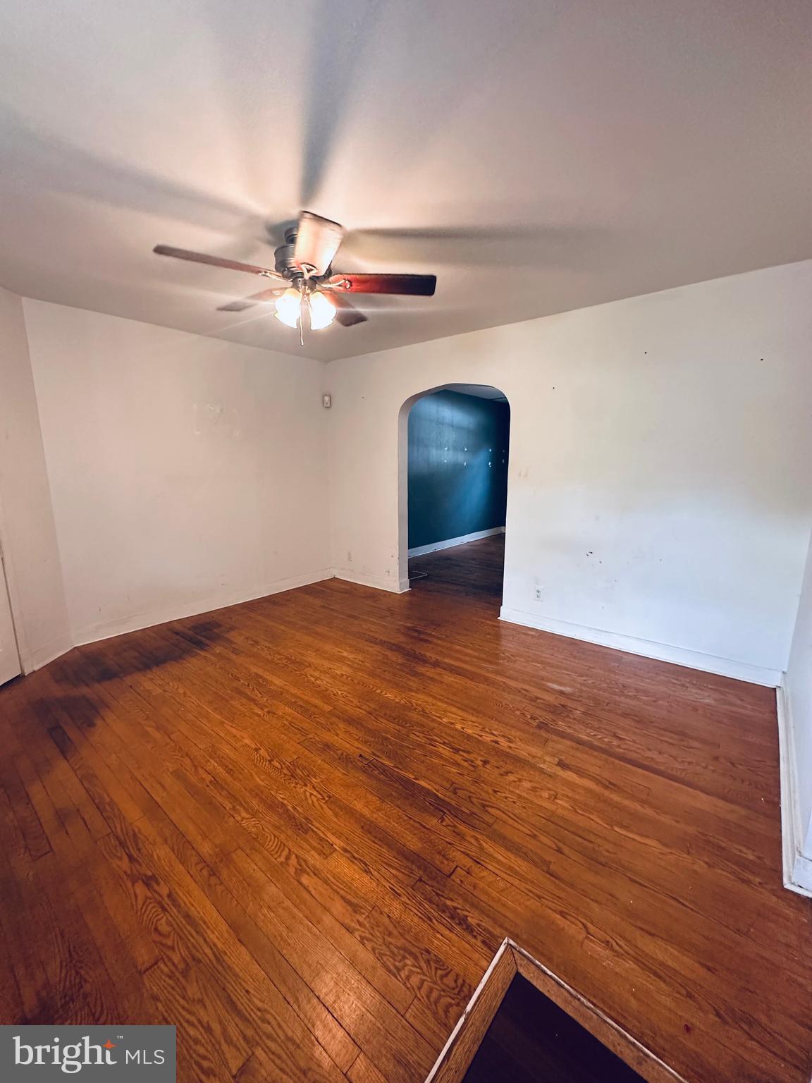 3804 Brooklyn Avenue Baltimore, MD 21225 - Photo 5 of 26 a view of an empty room with a chandelier fan and wooden floor