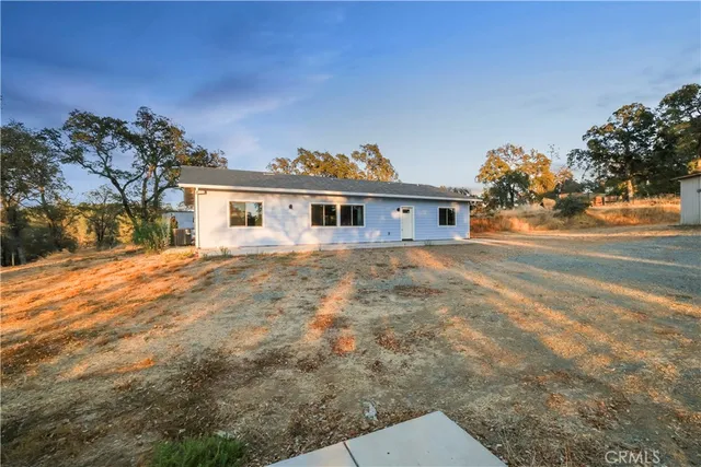 a view of house with yard and trees in the background